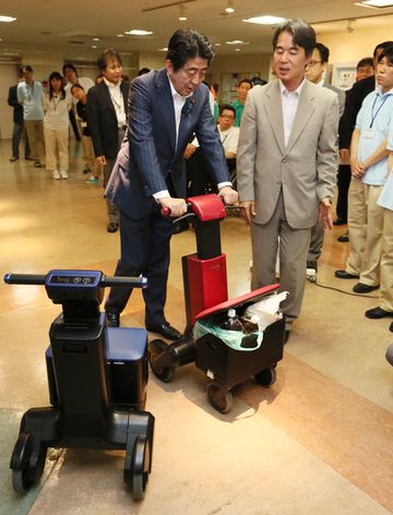 安倍总理视察了应用机器人的工厂和护理设施。