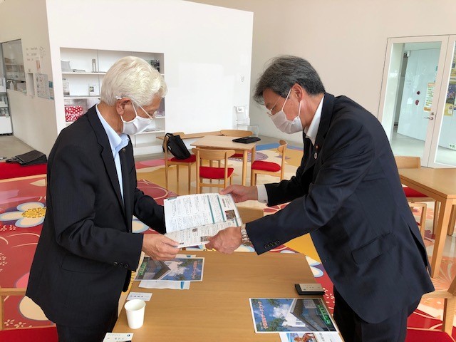 小山田市長（左）に「ふるさとづくり事例集」を手交し、南部裂織保存会の取組が掲載されている旨を説明している様子