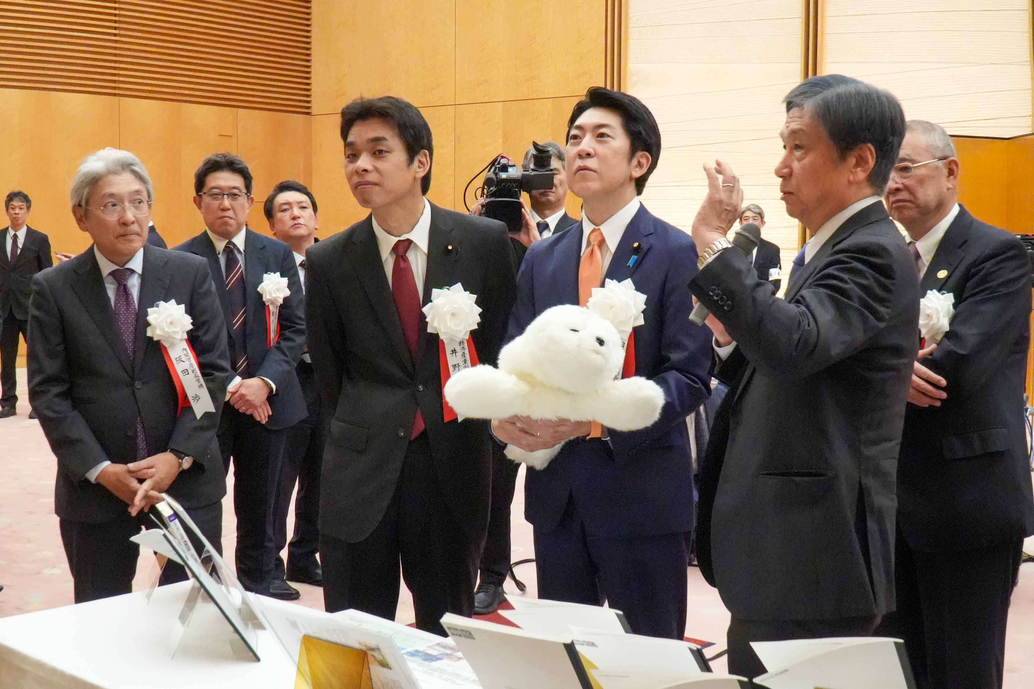 受賞者展示ブースを観覧する佐藤官房副長官３