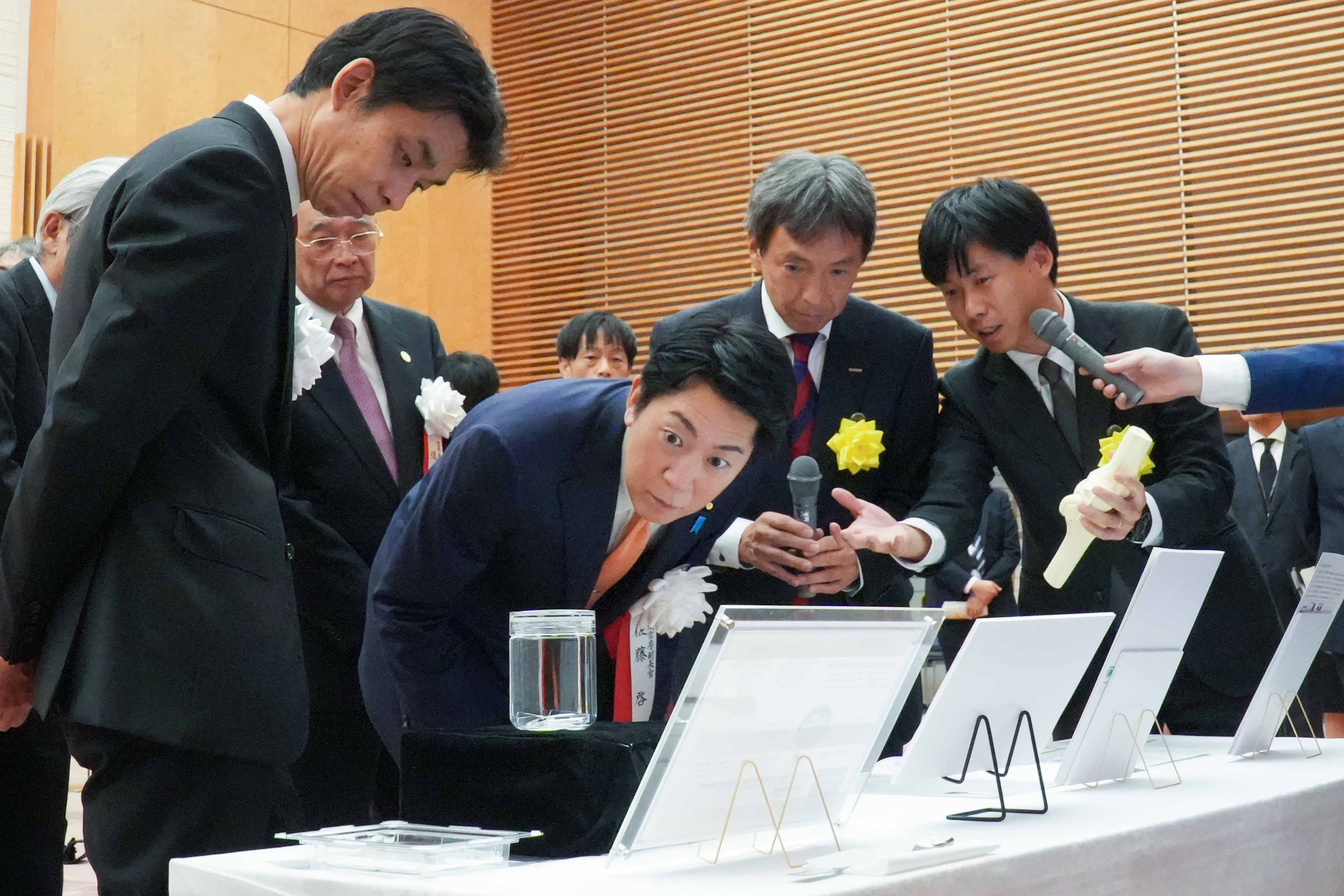 受賞者展示ブースを観覧する佐藤官房副長官５