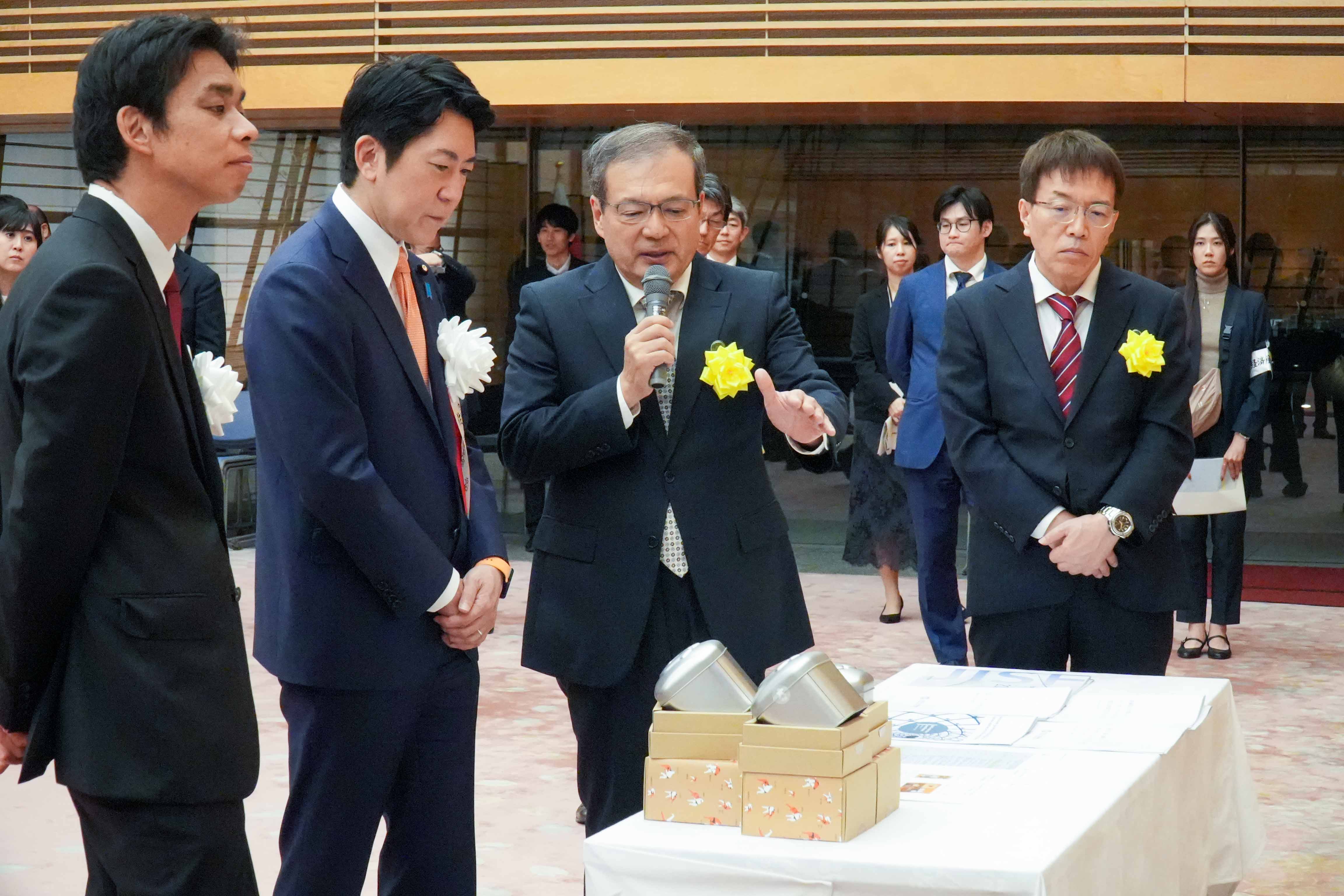 受賞者展示ブースを観覧する佐藤官房副長官６