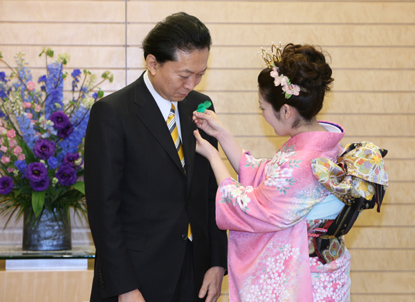さくらの女王に緑の羽根をつけてもらう鳩山総理の写真